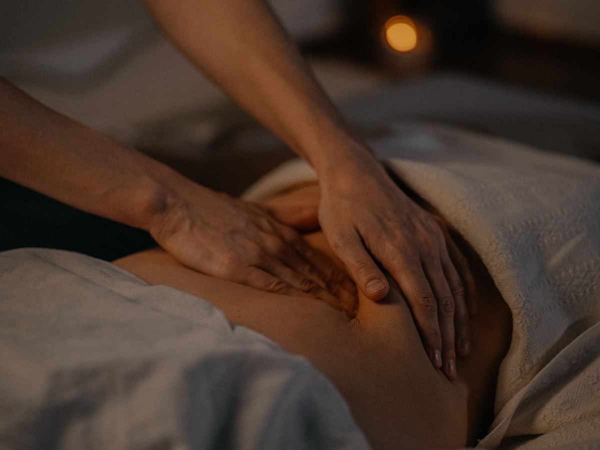 Visceral work: Kira’s hands on a client’s belly in candlelight